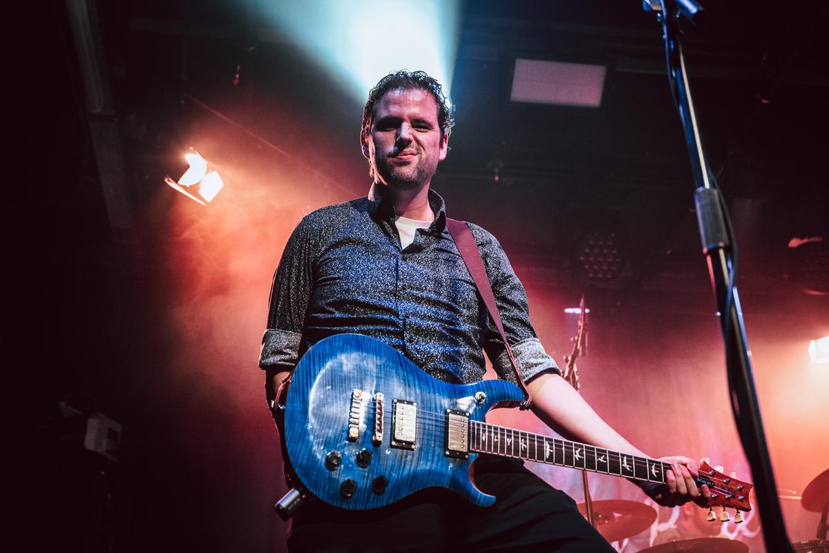 Guitarist with a blue guitar in red stage light