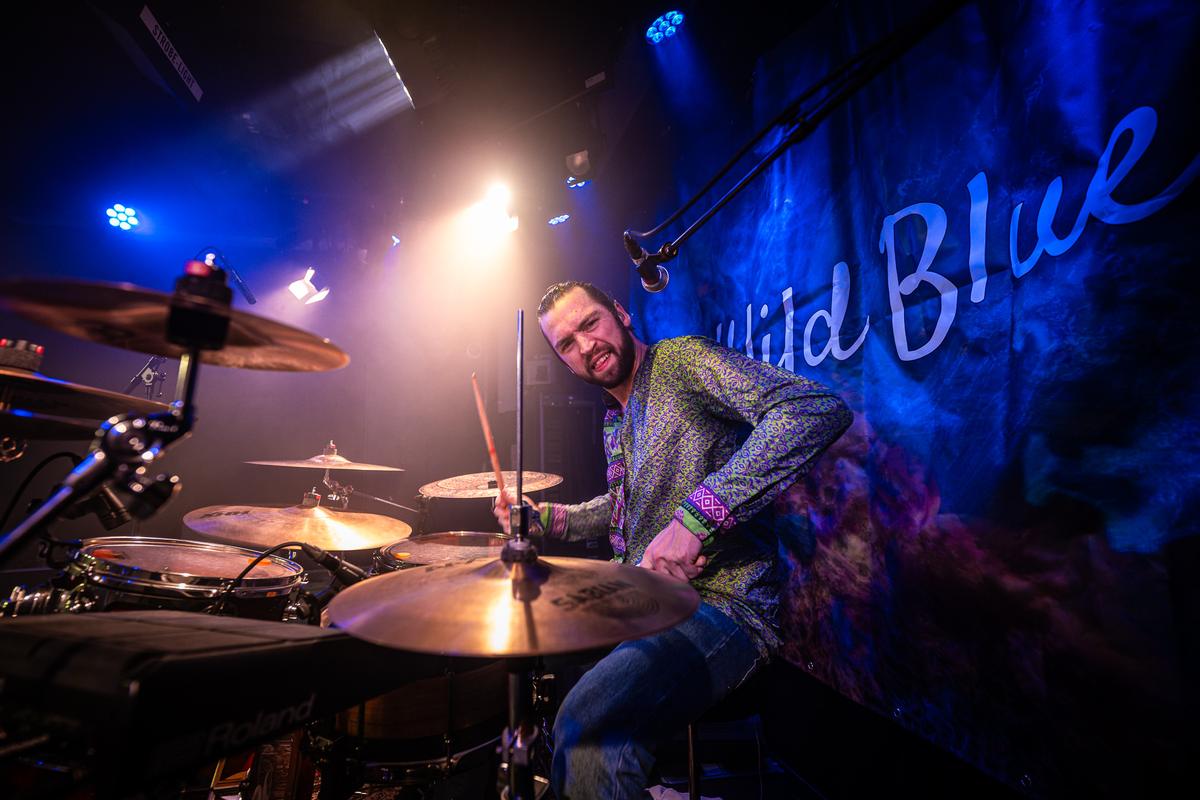 Drummer behind the kit in front of The Wild Blue banner